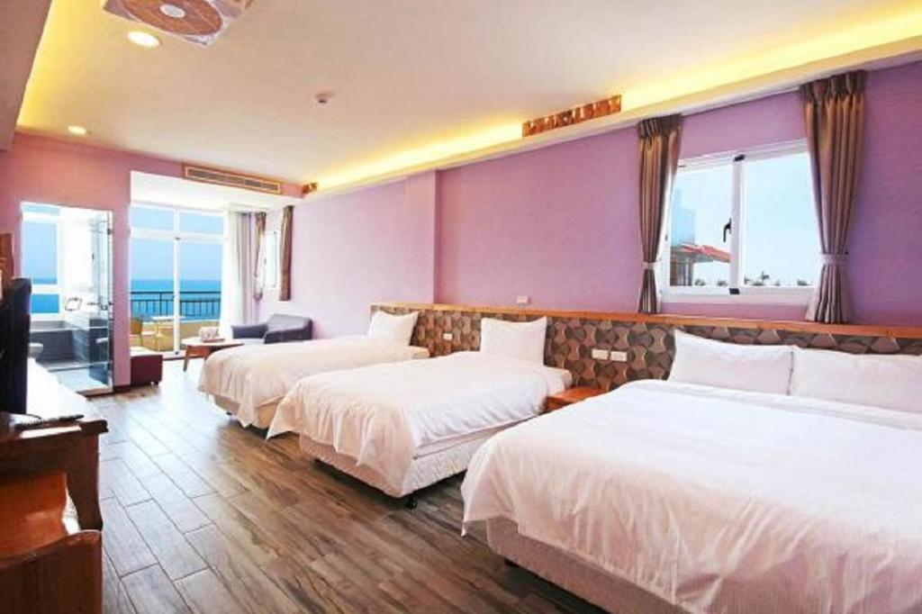 a hotel room with three beds and a balcony at Taitung Sea Wall Homestay in Taitung City