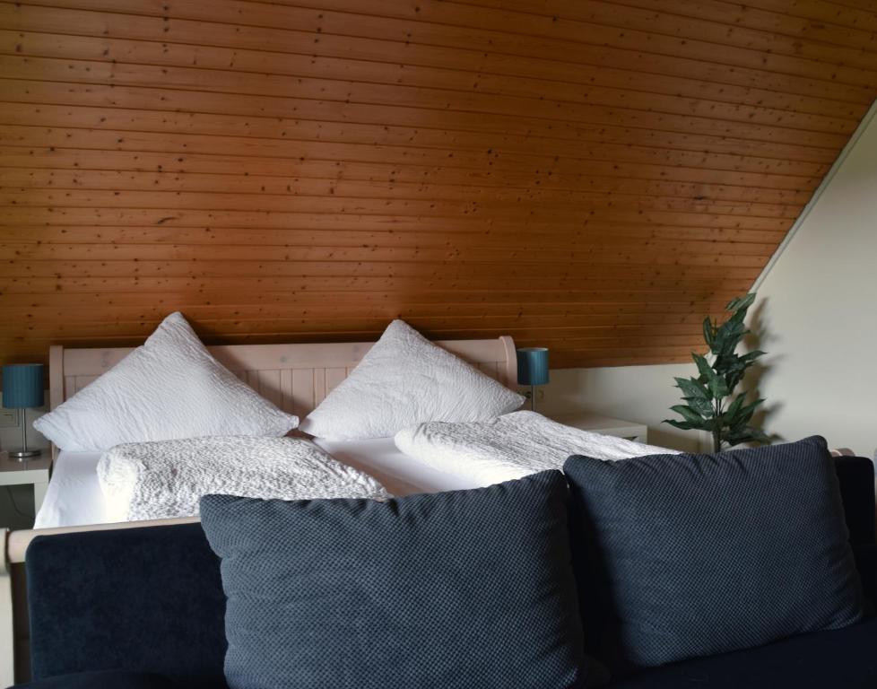 a bed with white pillows and a wooden ceiling at Pension am See in Schluchsee