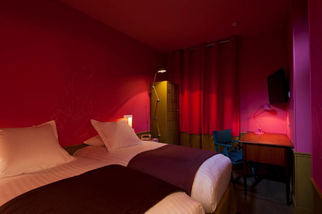 a bedroom with two beds and a desk and pink lights at Hôtel Crayon in Paris