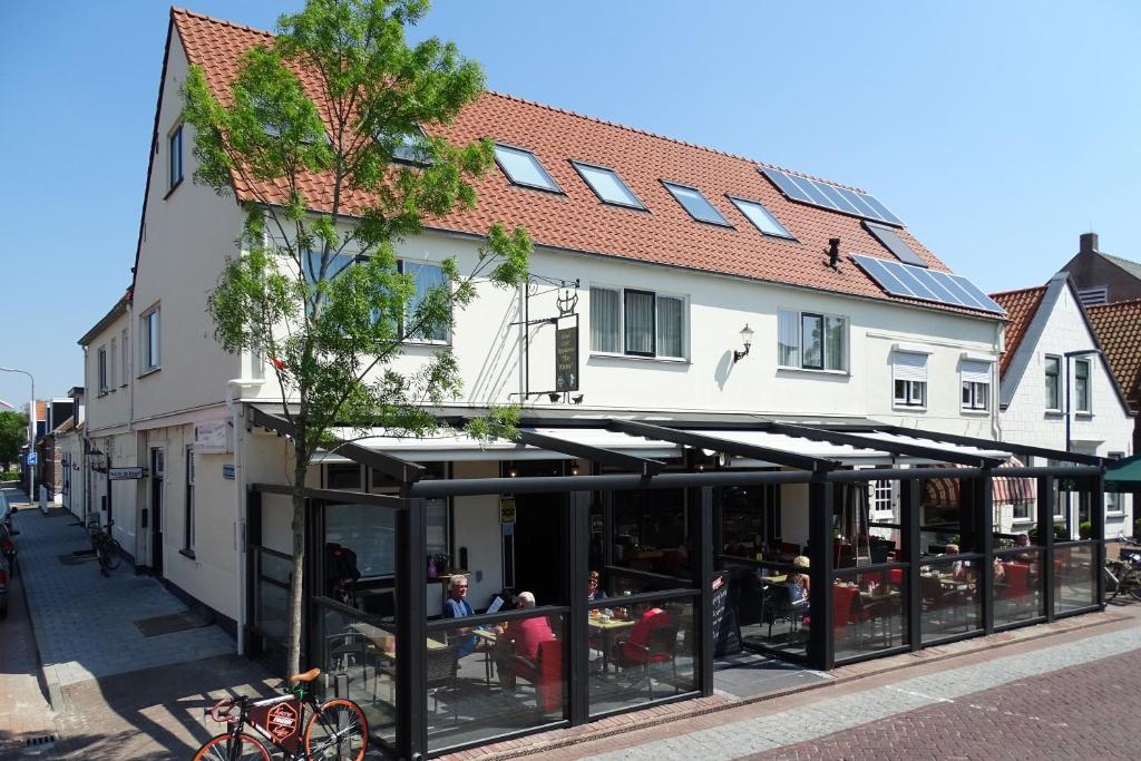 un edificio con gente sentada en mesas delante de él en Hotel Café Restaurant "De Kroon" en Wissenkerke
