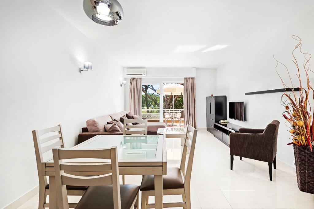 a dining room and living room with a table and chairs at Victory Village 9F in Quinta do Lago