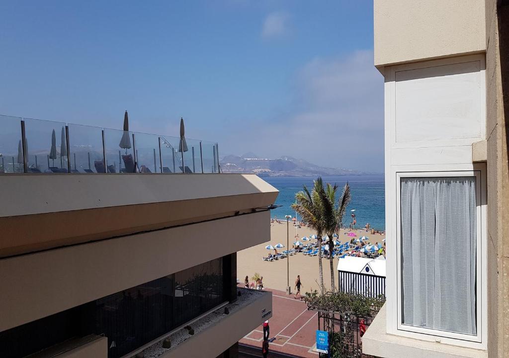 ラスパルマス・デ・グランカナリアにあるMarlenghi Apartments 8 2Aのバルコニー付きの建物からビーチの景色を望めます。