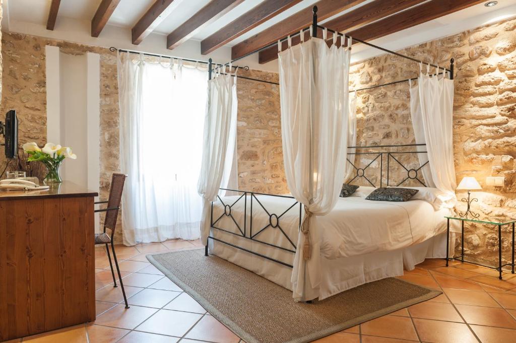 a bedroom with a canopy bed in a stone wall at Hotel Can Simo in Alcudia
