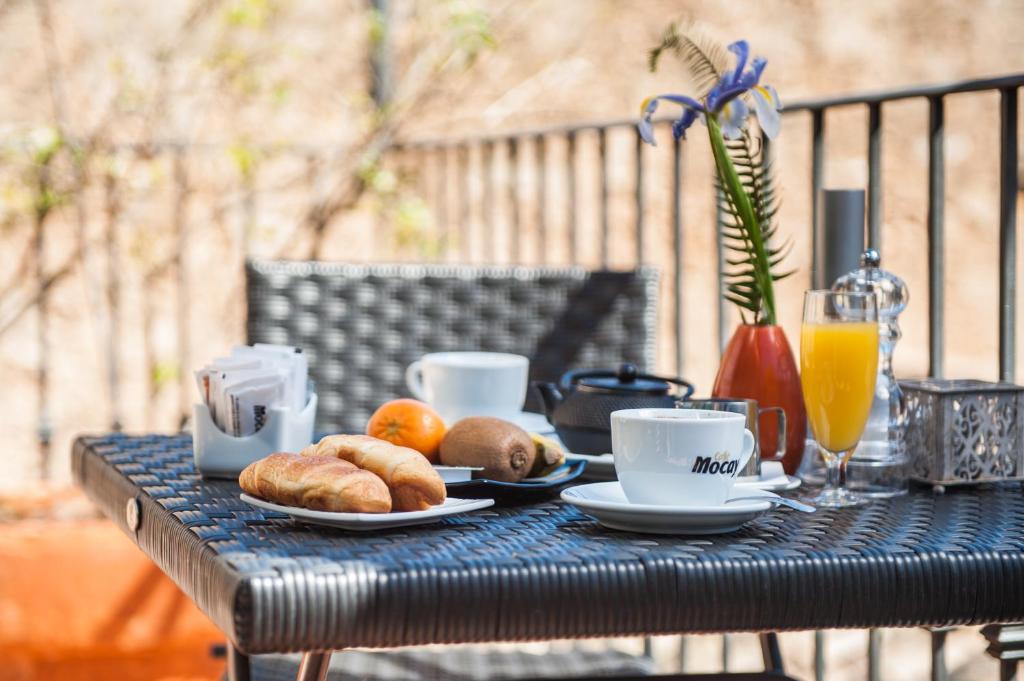 a table with a breakfast of croissants and coffee cups at Hotel Can Simo in Alcudia