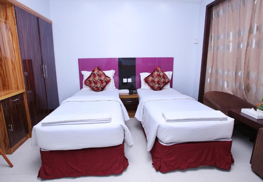 two beds in a hotel room with white and red pillows at Zagy Hotel in Dubai
