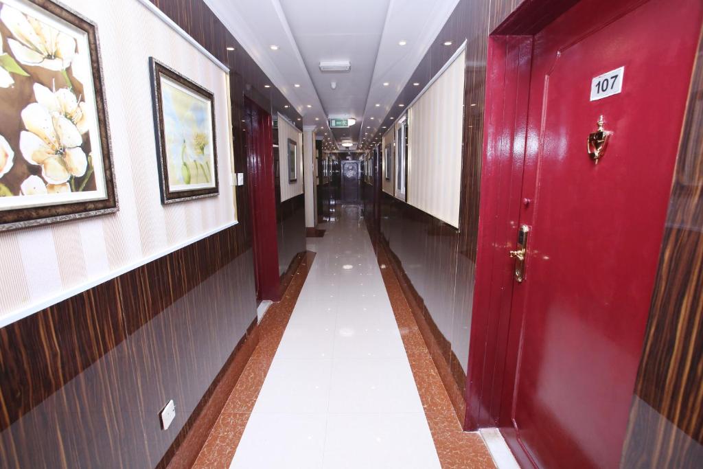 a hallway with a red door and a long corridor with paintings at Zagy Hotel in Dubai