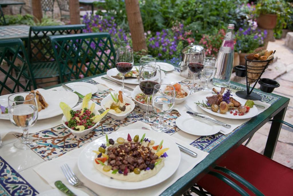 a table with plates of food and glasses of wine at The American Colony Hotel - Small Luxury Hotels of the World in Jerusalem