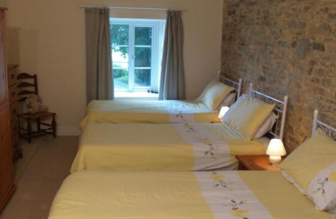 três camas num quarto com uma janela em Coach House Cottage em Merton