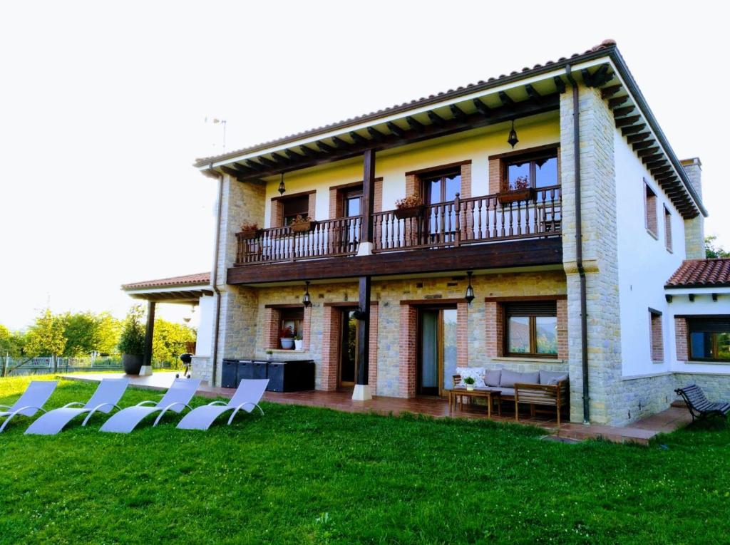 una casa con un prato e sedie di fronte di Villa Tiviti a Oviedo