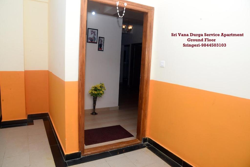 a hallway with a mirror and a vase of flowers at Sri Vana Durga Service Apartment in Sringeri