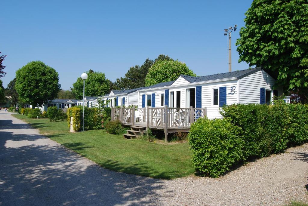 une maison blanche avec terrasse couverte dans une rue dans l'établissement Camping Le Walric, à Saint-Valery-sur-Somme