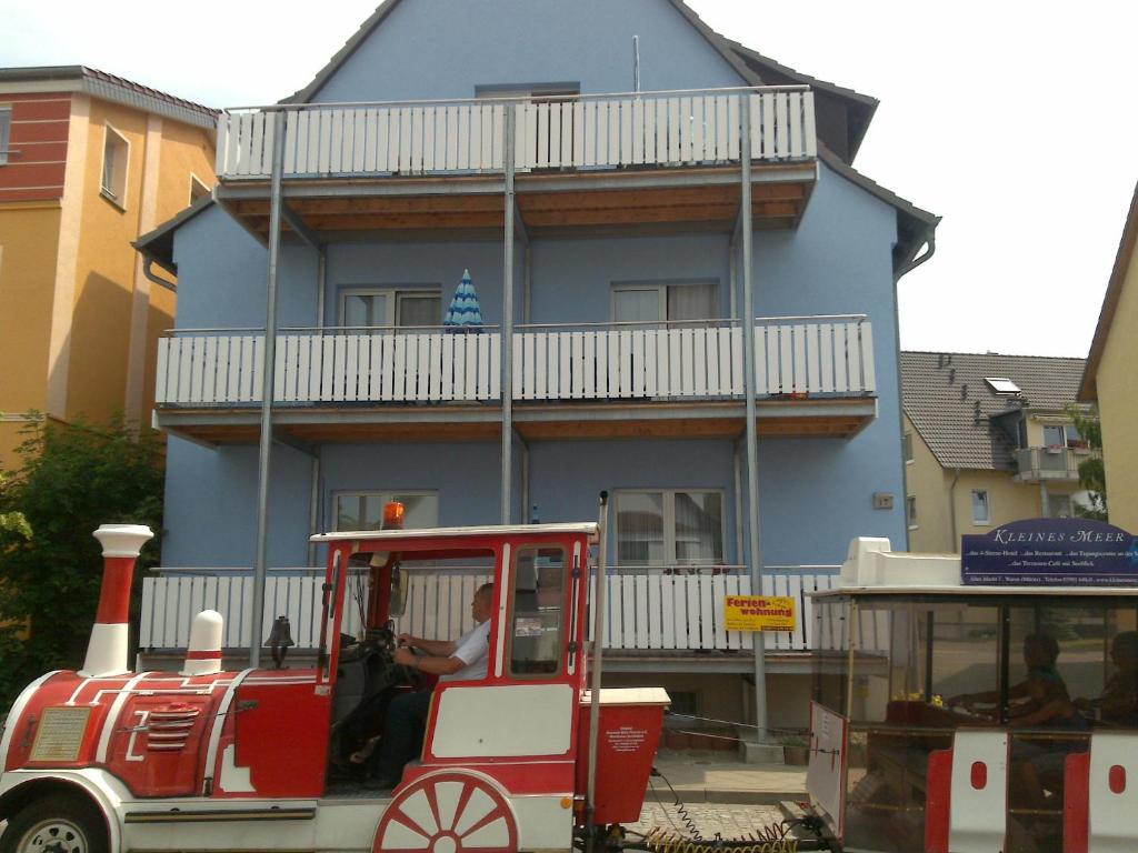 un petit train rouge devant un bâtiment bleu dans l'établissement Ferienwohnung Am Müritz Seeufer, à Waren