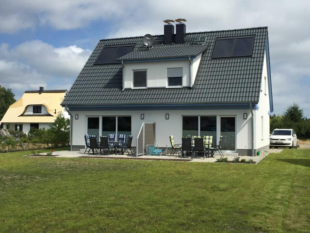 een wit huis met een zonnedak en stoelen bij Ferienhaus Sinha_SOMM in Ostseebad Karlshagen