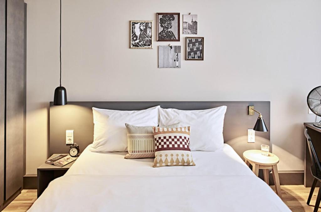 a bedroom with a large white bed with pillows at Bold Hotel München Zentrum in Munich