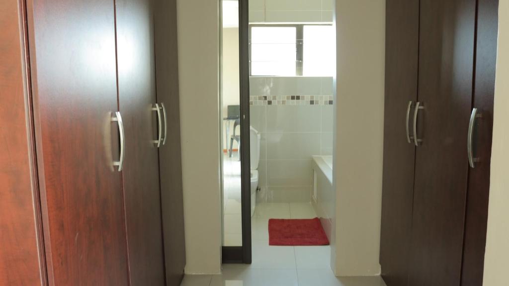 a bathroom with two wooden doors and a shower at Tap's Home Away from Home in Gaborone