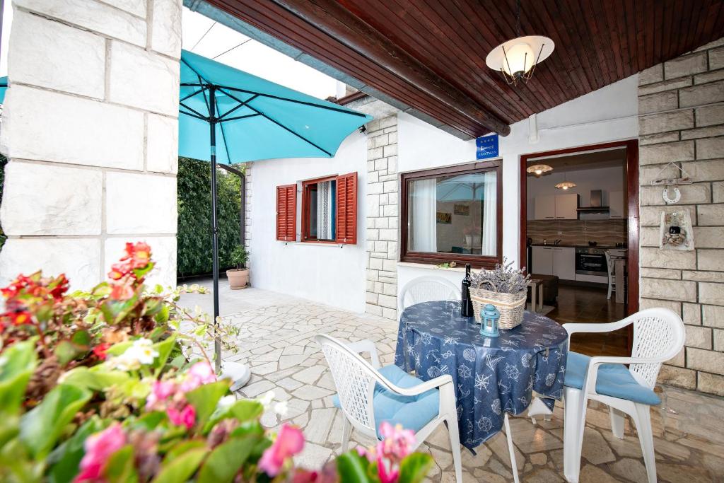un patio con mesa, sillas y sombrilla en Apartment Mediteraneo, en Opatija