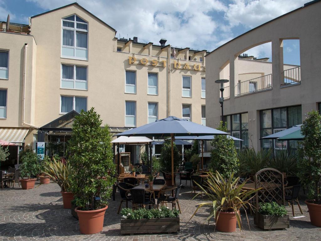 ein Hotel mit Tischen und Sonnenschirmen vor einem Gebäude in der Unterkunft Posthaus Hotel Residenz in Kronberg im Taunus