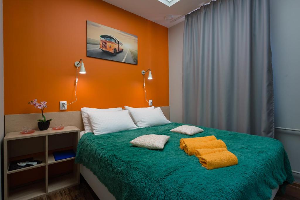 Schlafzimmer mit grünem Bett und orangefarbenen Wänden in der Unterkunft Hostel Kislorod O2 in Jaroslawl