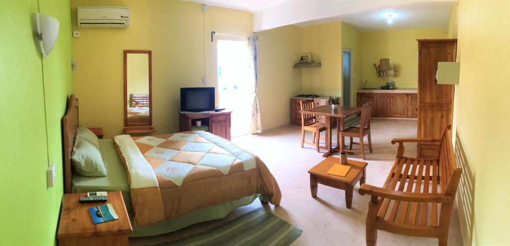 a bedroom with a bed and a table and chairs at Le Rosier in Trou d'Eau Douce