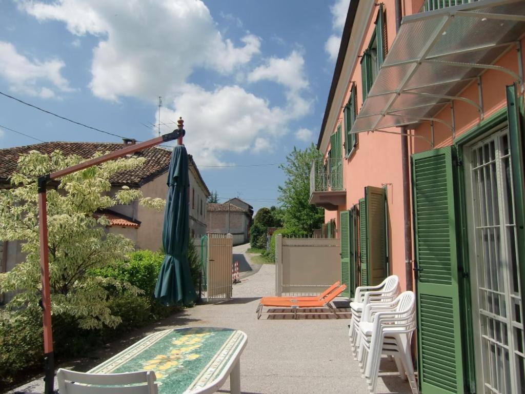 patio z białymi krzesłami i różowym budynkiem w obiekcie B&B LA VIGNA DI TINA w mieście Costigliole dʼAsti