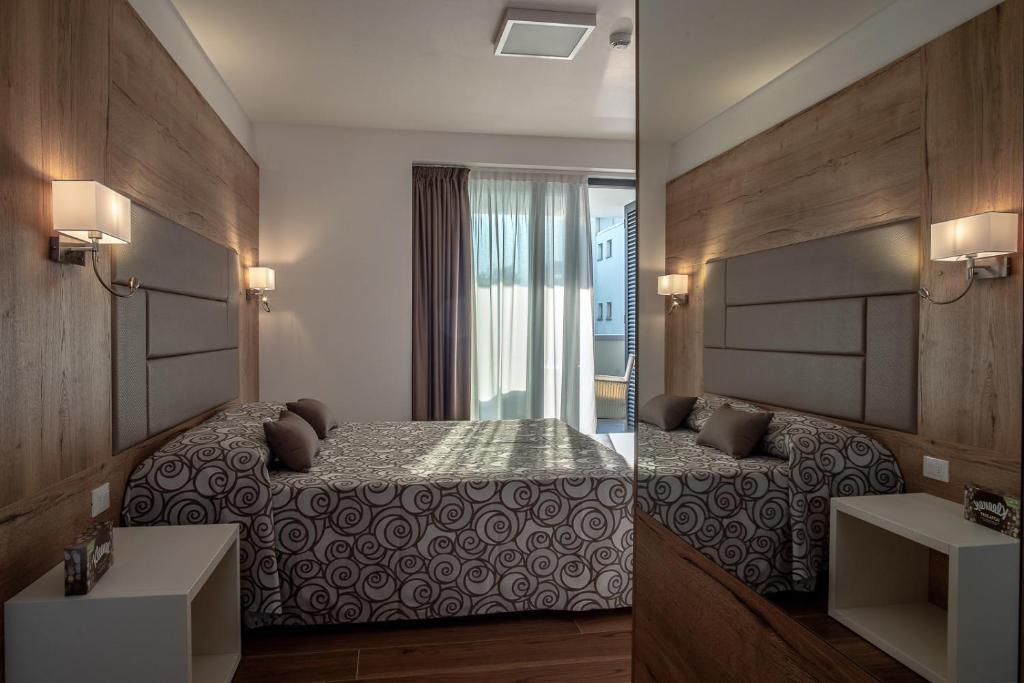 Aparthotel Miramare في غرادو: صورتين لغرفة نوم مع سرير ومغسلة