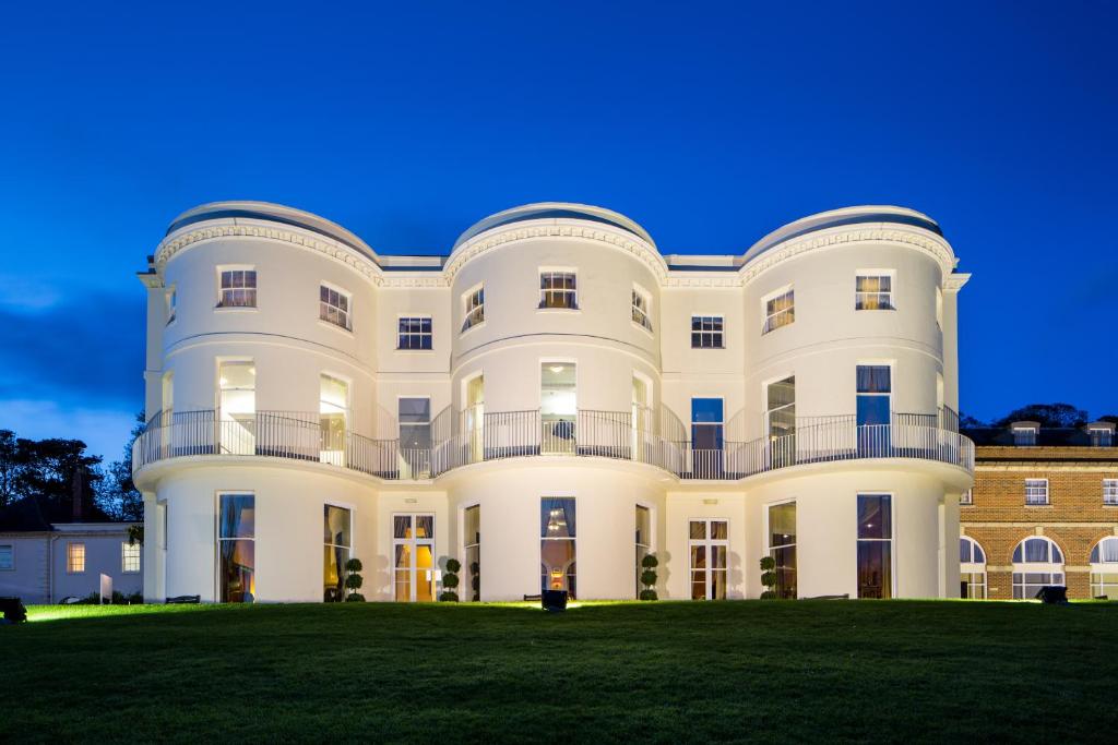 a large white building on a grass field at Mercure Gloucester Bowden Hall Hotel in Gloucester
