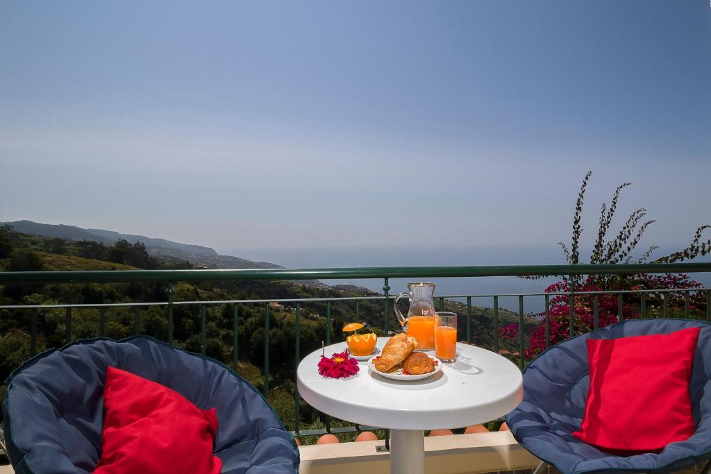 a table with food and orange juice on a balcony at Casa do Miradouro in Ponta do Sol