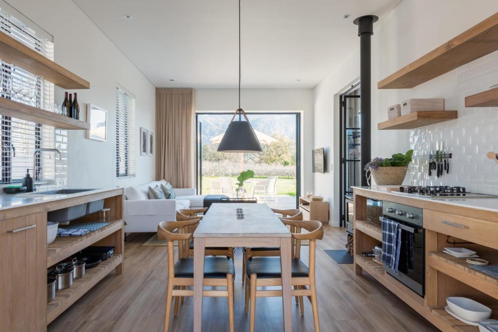 una cucina e un soggiorno con tavolo e sedie di La Chataigne Wines & Guest Cottages a Franschhoek