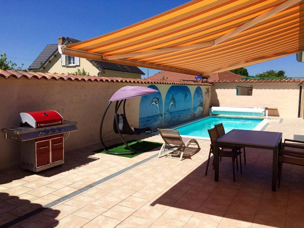 een patio met een tafel, een parasol en een zwembad bij Charmant Studio en Champagne - Sparkling-Life in Matougues