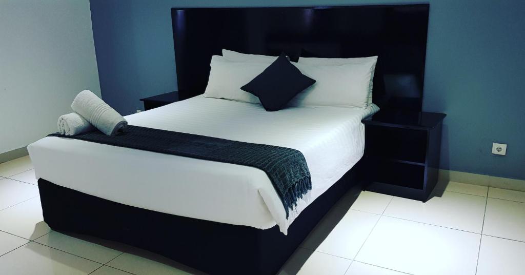 a bedroom with a large white bed with a black headboard at Hotel Al-Khalil Matola in Matola