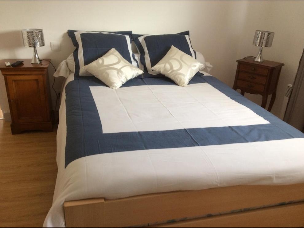 a large bed with blue and white sheets and pillows at Cosy&#39;s Sable in Larmor-Plage