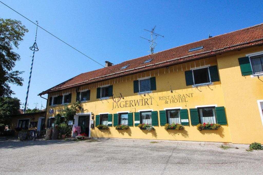 ein gelbes Gebäude mit einem Schild an der Seite in der Unterkunft Gasthof Jägerwirt in Hohenschäftlarn
