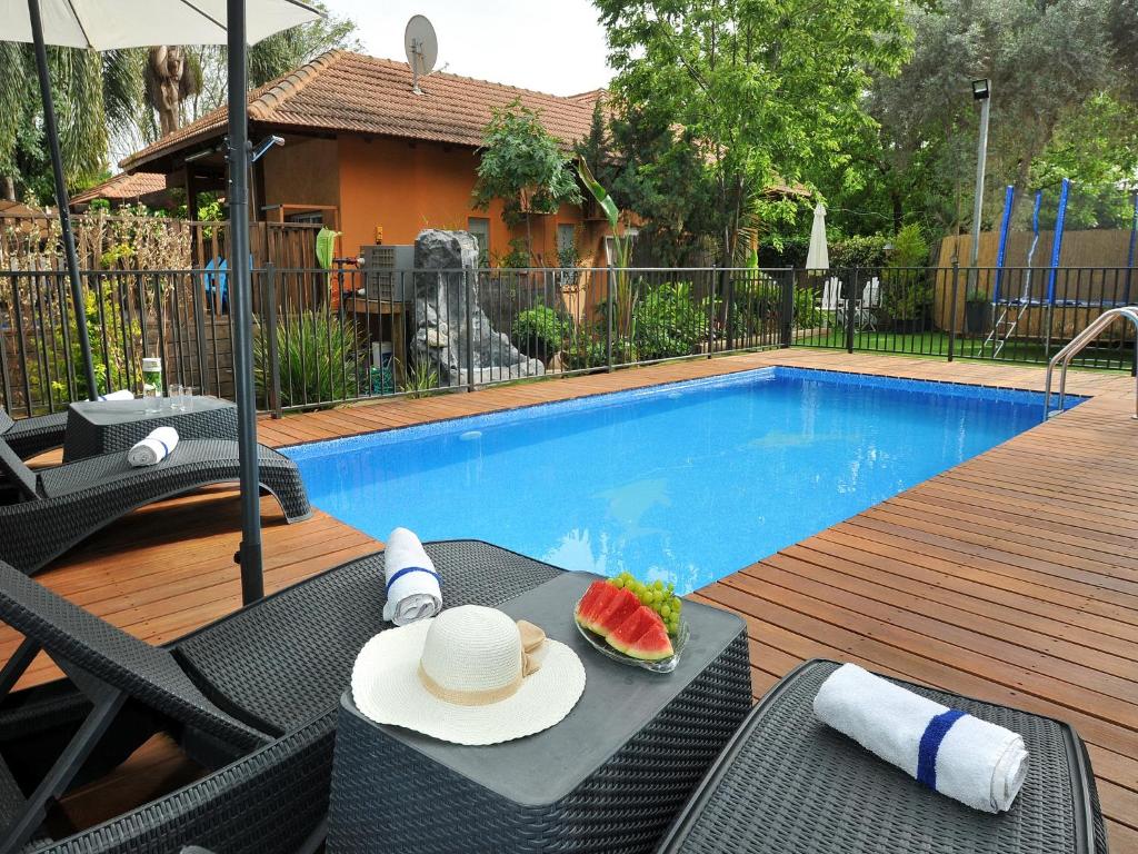 una mesa con un sombrero y un sándwich junto a una piscina en Love & Lemons en Yesod Hamaala