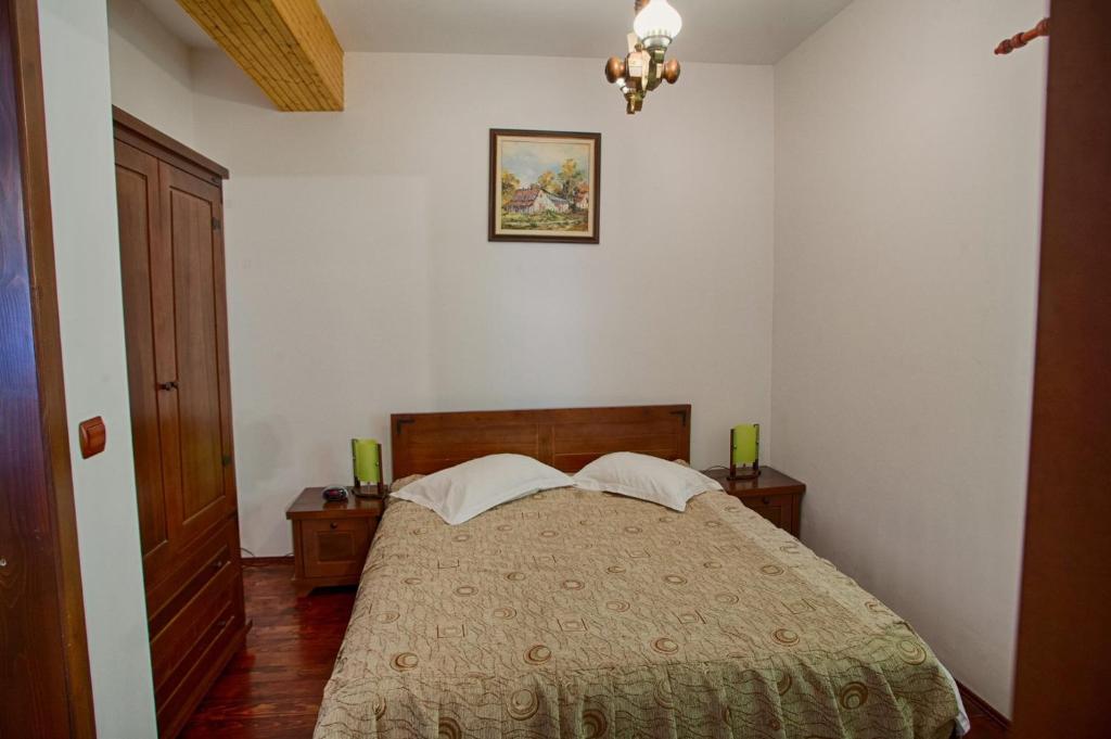 a bedroom with a bed with two tables and a picture on the wall at Vila Ursul in Ciungetu