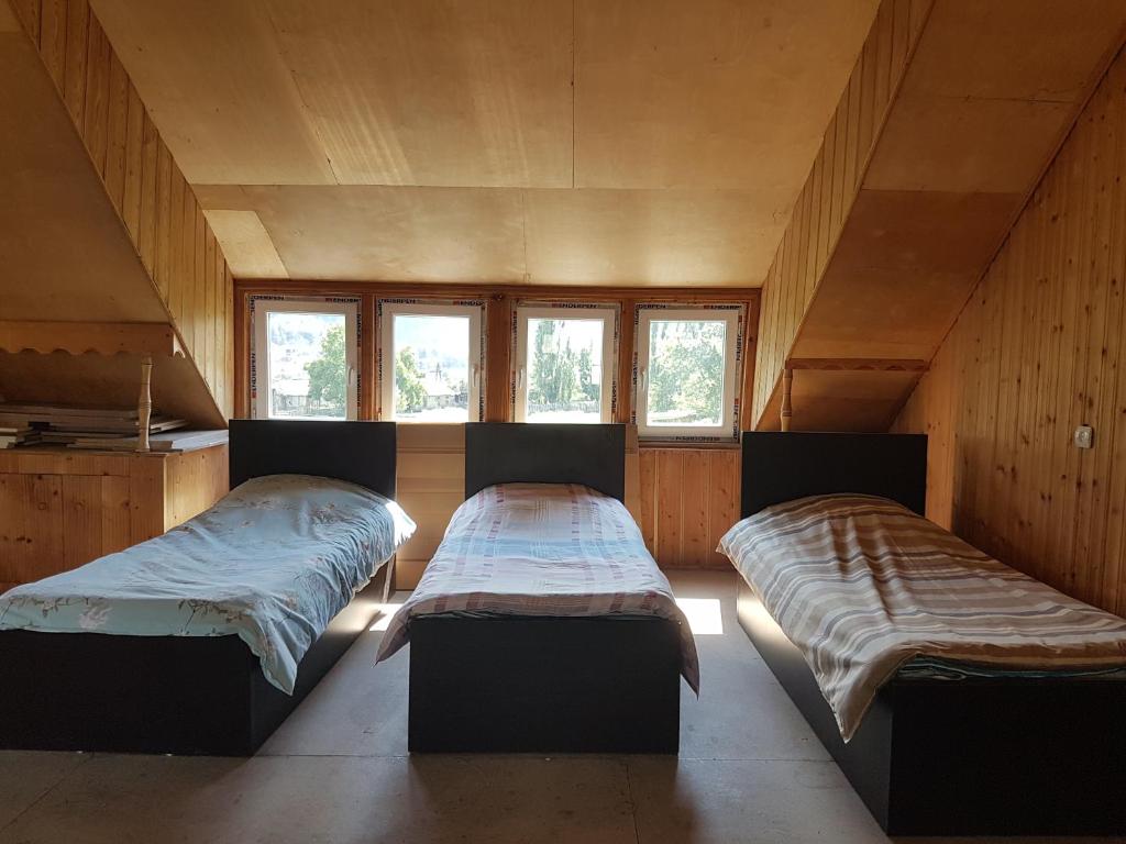 2 Betten in einem Zimmer mit Holzwänden und Fenstern in der Unterkunft Hostel SvanLand in Mestia