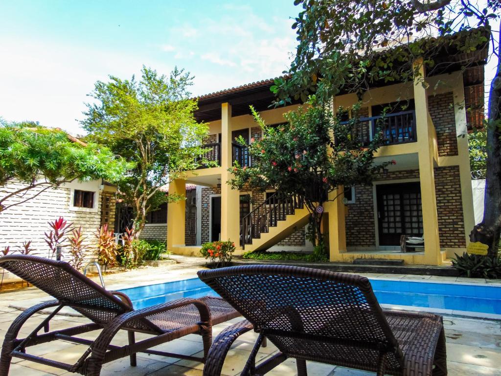 a house with two chairs next to a swimming pool at Chalés Aguaí in Natal