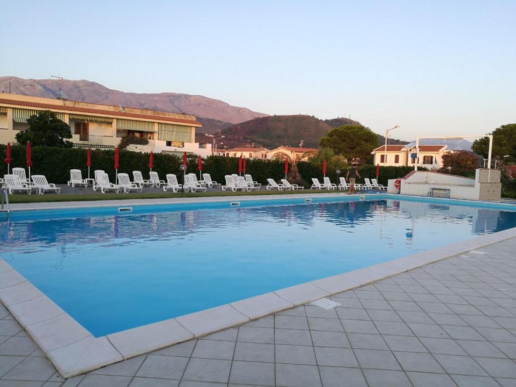 a large blue swimming pool with chairs and a building at House Aurora in San Nicola Arcella