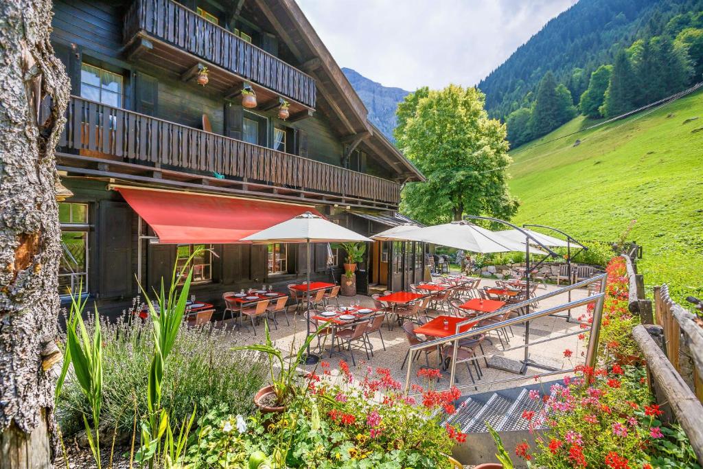 a restaurant with tables and umbrellas in front of a building at Guest House du Grand Paradis - On Piste in Champéry