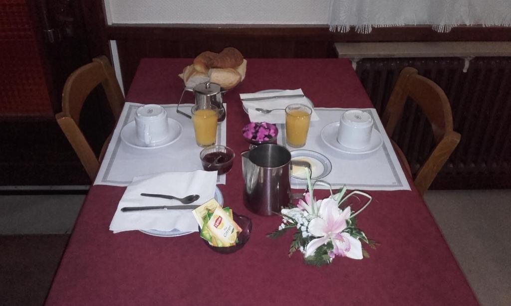 une table avec un chiffon de table violet, deux assiettes et du jus d'orange dans l'établissement Logis Hôtel Beauséjour, à Chauvigny