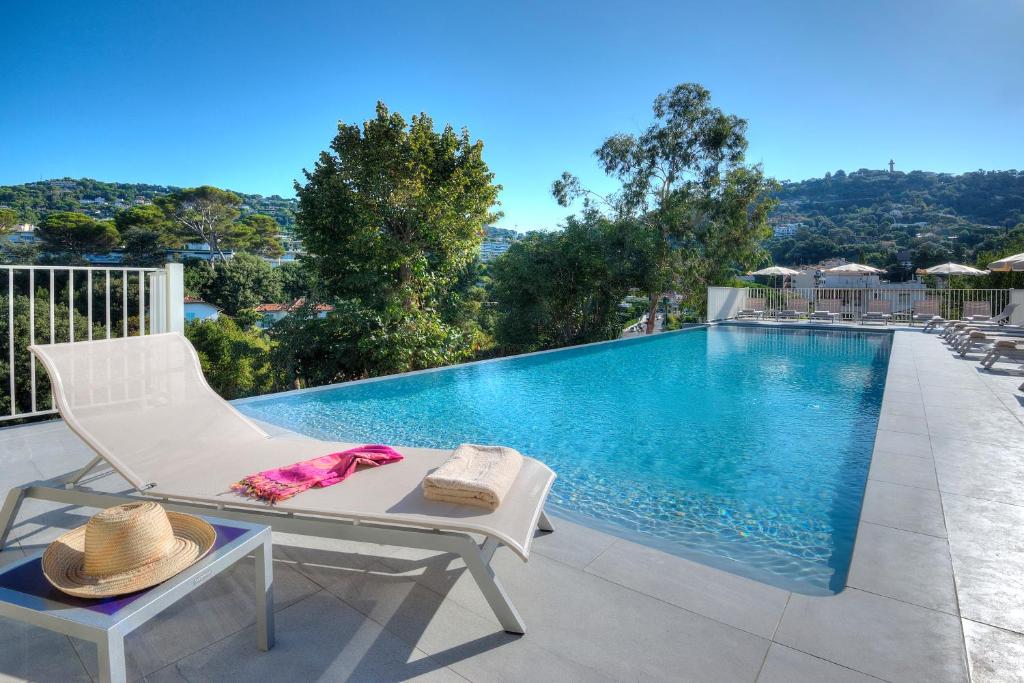 - une piscine avec une chaise blanche et une table dans l'établissement La Bastide de l'Oliveraie, à Cannes