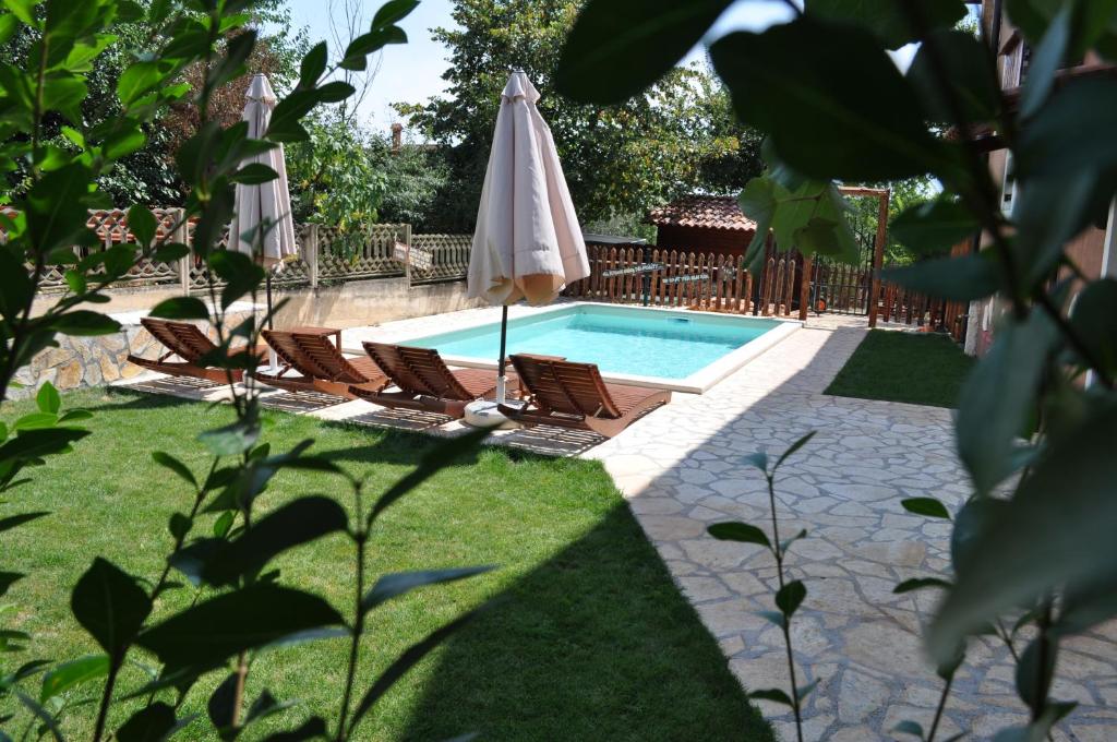 uma piscina com duas cadeiras e um guarda-sol em Apartments Oliva em Fiorini