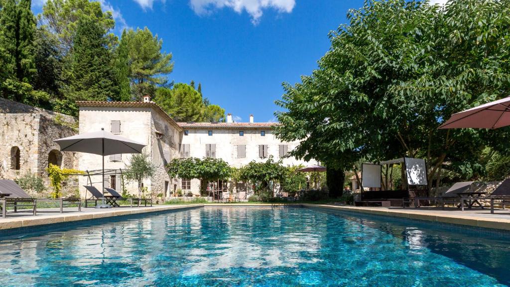 a swimming pool with chairs and umbrellas in front of a building at Moulin Sainte Anne in Grasse