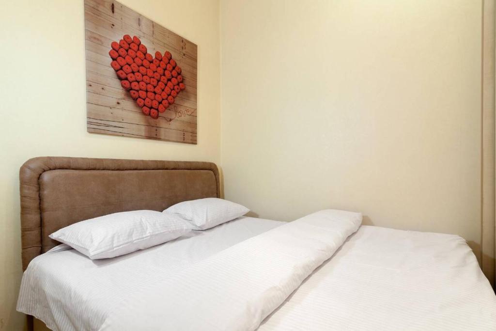 łóżko z dwoma białymi poduszkami i sercem na ścianie w obiekcie Light-studio apartment in the center city w Lwowie