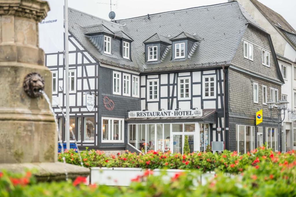 ein schwarzweißes Gebäude mit einer Statue davor in der Unterkunft Hotel Starke in Brilon