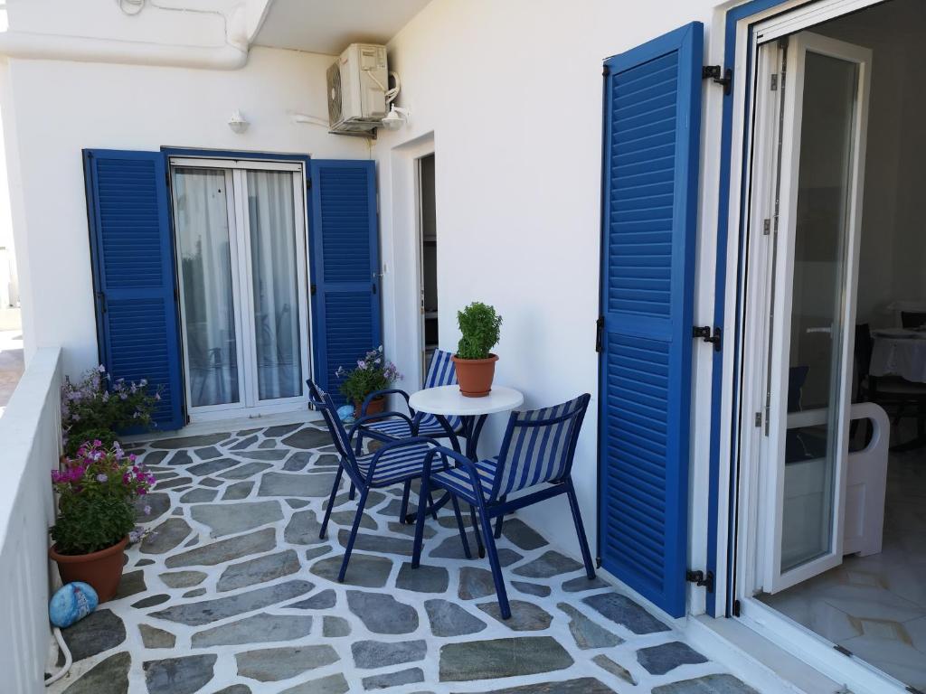 een patio met blauwe luiken en een tafel en stoelen bij Minas House Antiparos in Antiparos Stad