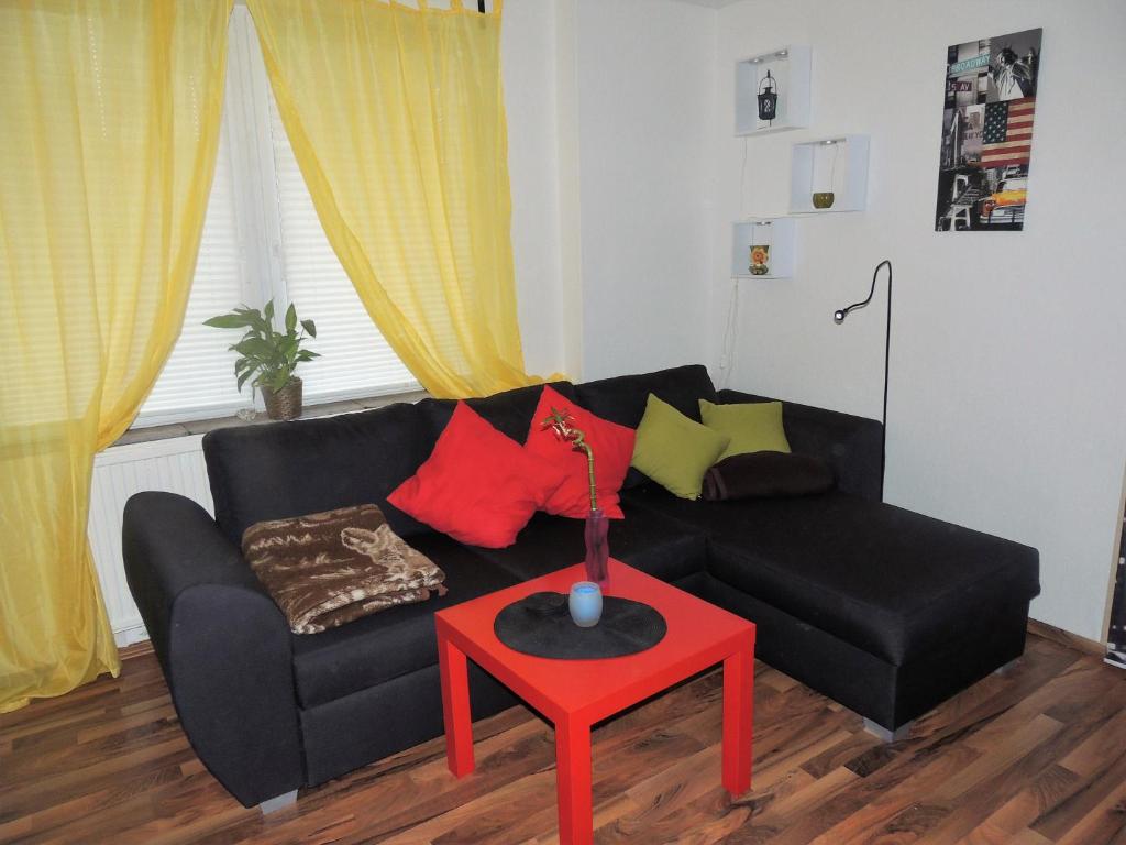 ラーデボイルにあるFerienwohnung Am Hausberg in Radebeulのリビングルーム(黒いソファ、赤いテーブル付)