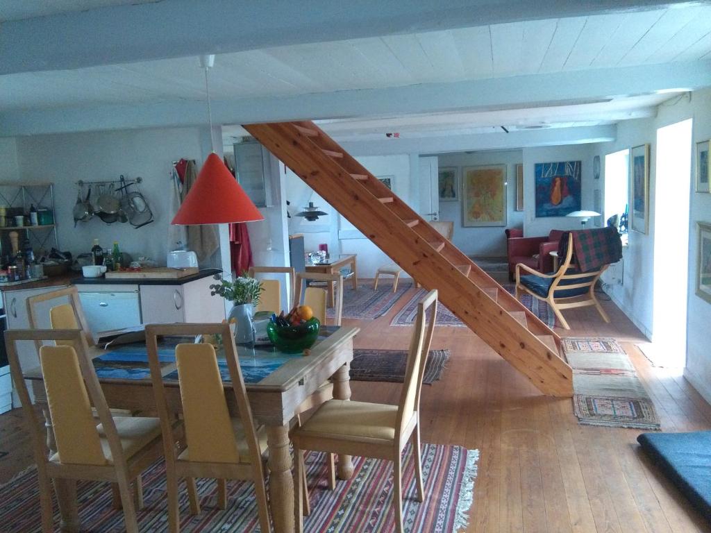 a dining room and living room with a table and a staircase at Langøhuset in Langebæk