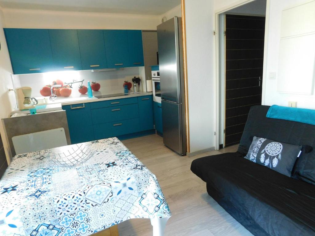 une cuisine avec des placards bleus et une table dans le salon dans l'établissement Le petit nid, à Lourdes