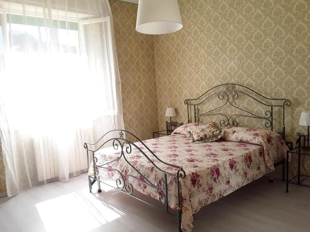 a bedroom with a bed with a floral bedspread and a window at Appartamento Elena in Lucca