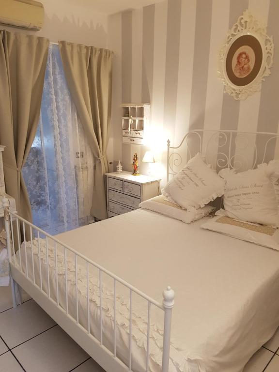 a white bed in a room with a window at La Cameretta in Ischia